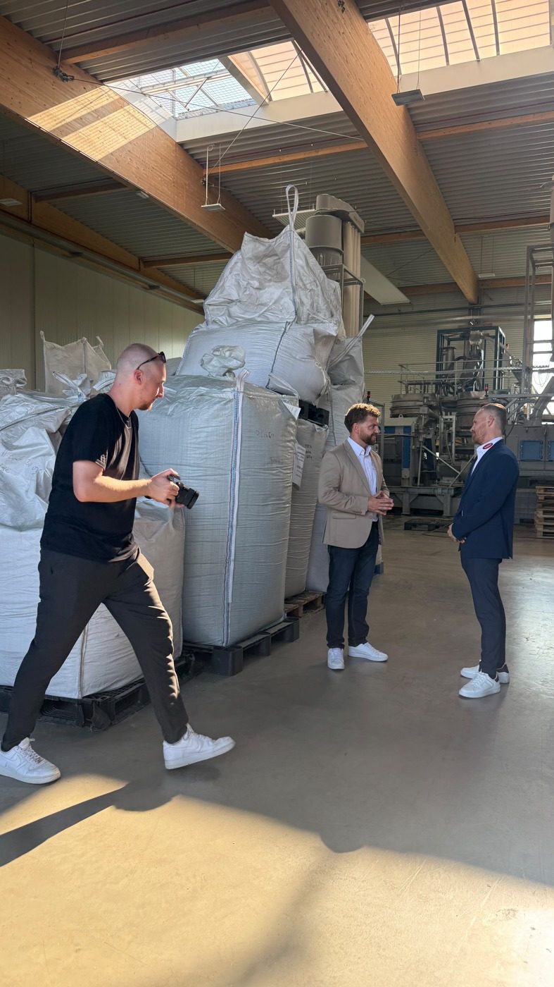 Mario Kaiser filmt ein Interview zwischen zwei Personen in einer Produktionshalle